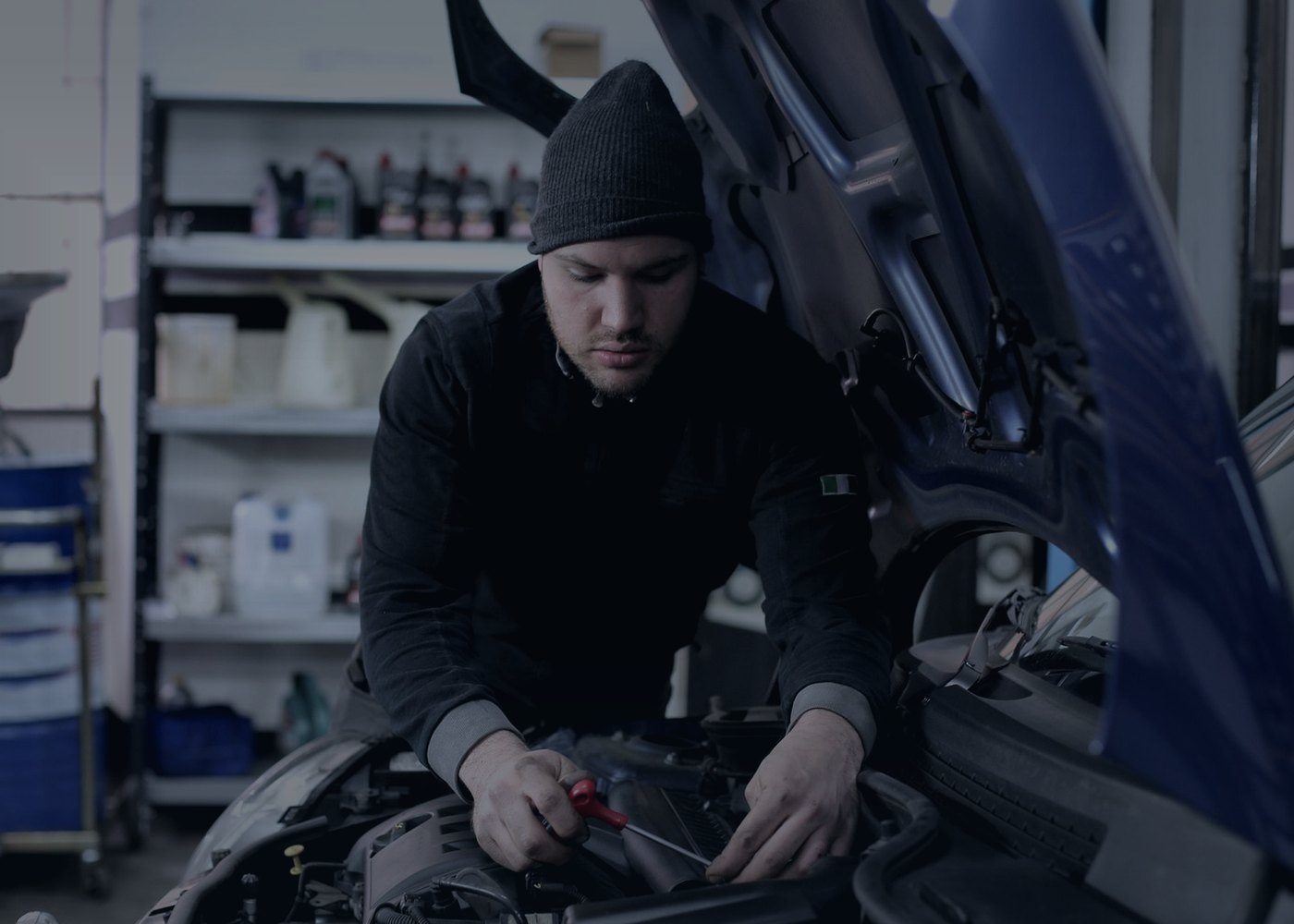 Mechanic working in a car engine bay with a screwdriver